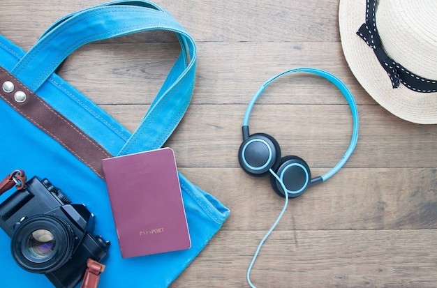 Flat lay travel items, bag, camera, passport, headphone and straw hat