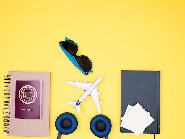 Flat lay of traveler kit on yellow background. books , sunglasses , passport and headphones