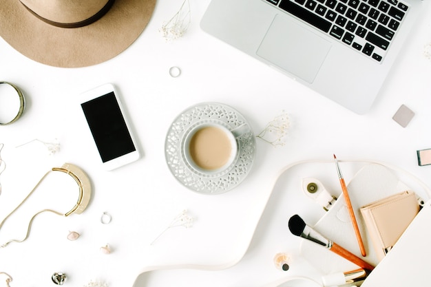 Flat lay trendy feminine home office workspace. Laptop, coffee cup, phone, purse, hat, female accessories