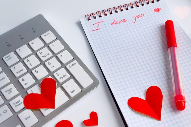 Flat lay valentines day in the office Red heart on white keyboard and table diary with the words