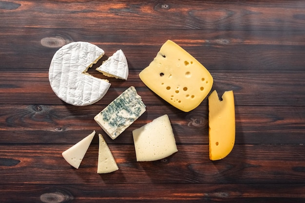 Flat lay Variety of large gourmet cheese wedges on a dark wooden background