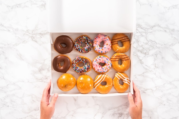 Flat lay. Variety of store-bought doughnuts in a white paper box.