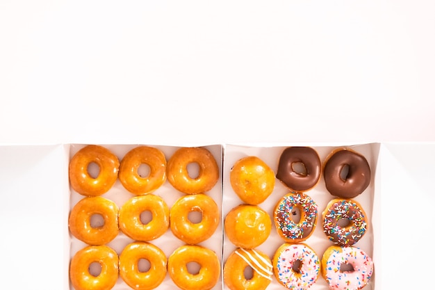 Flat lay. Variety of store-bought doughnuts in a white paper box.