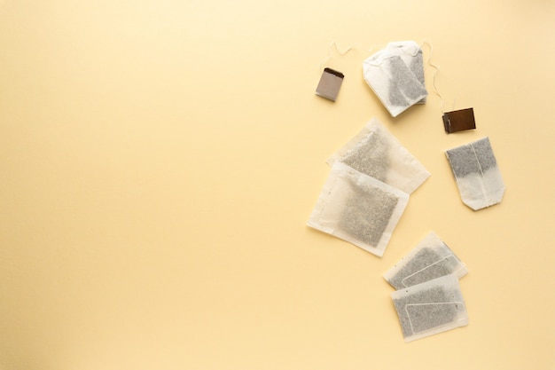 Flat lay of various tea bags on beige background, space for text