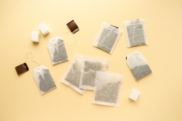 Flat lay of various tea bags on beige background, top view.