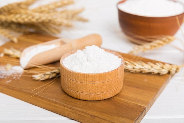 Flat lay of Wheat flour in wooden bowl with wheat spikelets on colored background world wheat crisis