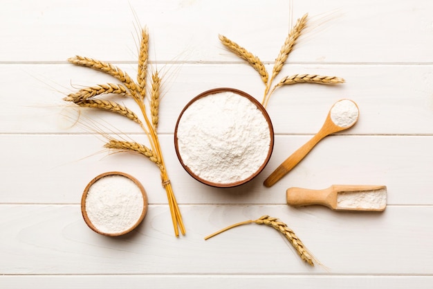 Flat lay of Wheat flour in wooden bowl with wheat spikelets on colored background world wheat crisis