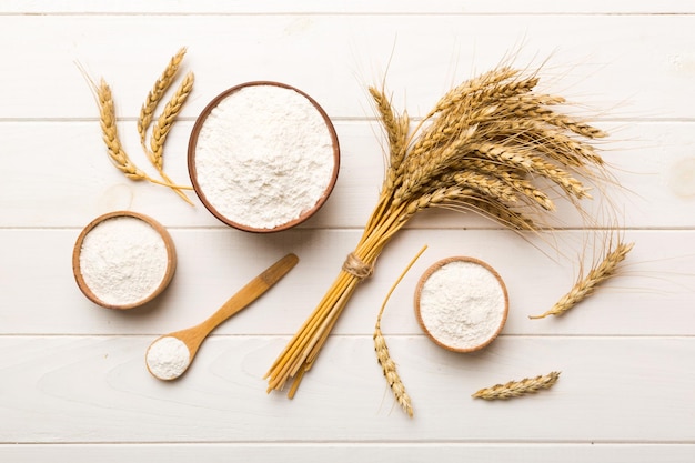 Flat lay of Wheat flour in wooden bowl with wheat spikelets on colored background world wheat crisis