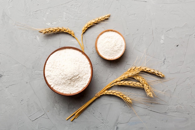 Flat lay of Wheat flour in wooden bowl with wheat spikelets on colored background world wheat crisis