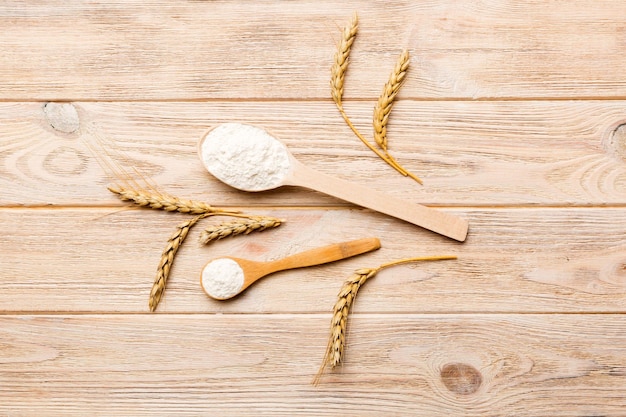 Flat lay of Wheat flour in wooden bowl with wheat spikelets on colored background world wheat crisis