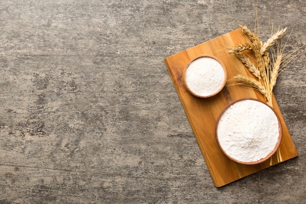 Flat lay of Wheat flour in wooden bowl with wheat spikelets on colored background world wheat crisis