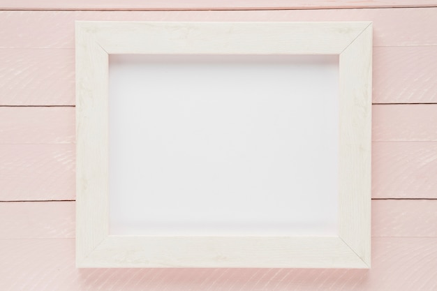 Flat lay white empty frame with wooden background