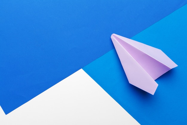 Flat lay of white paper plane and blank paper on pastel blue color background