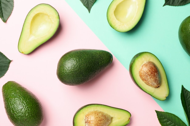 Flat lay with avocado and leaves on two tone background, top view