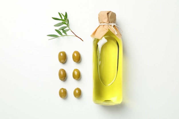 Flat lay with bottle of olive oil, olives and leaves on white, space for text