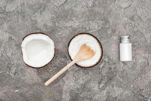 Flat lay with coconuts wooden spoon and coconut cream on grey textured background