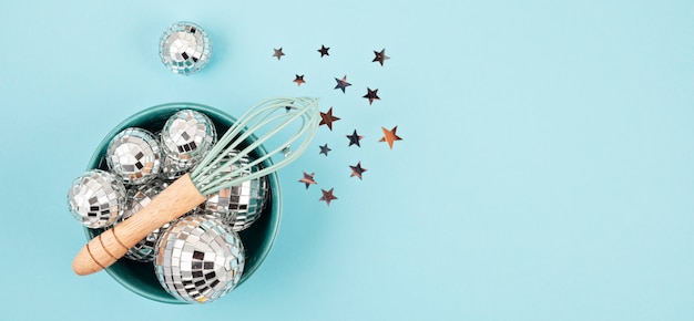 Flat lay with disco balls in the bowl with whisk. Party, fun, celebration planning