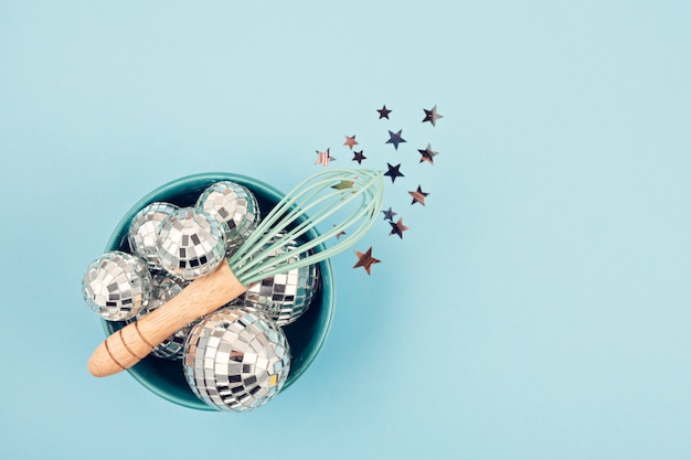 Flat lay with disco balls in the bowl with whisk. 