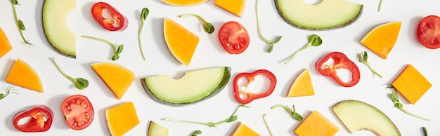 Flat lay with microgreens cut vegetables and avocado slices on white background panoramic shot