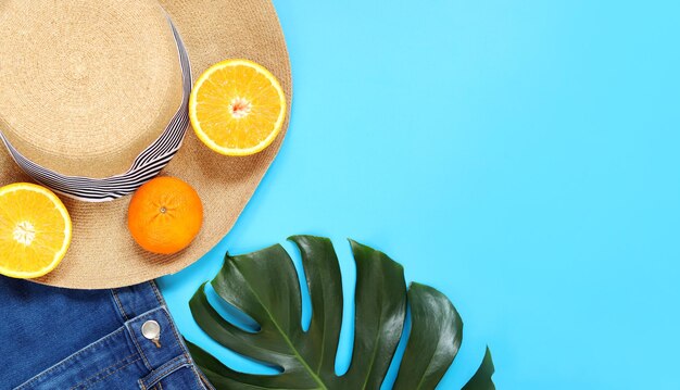 Flat lay with monstera leaf summer women039s hat shorts and oranges Summer concept copy space