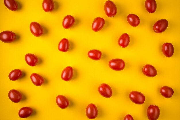 Flat lay with red cherry tomatoes on yellow 