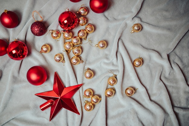 Flat lay with red christmas balls, golden christmas balls and christmas candy canes on the plaid.