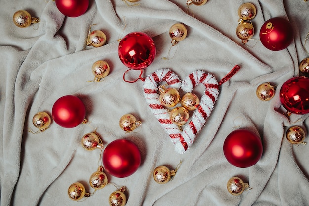 Flat lay with red christmas balls, golden christmas balls and christmas candy canes on the plaid.