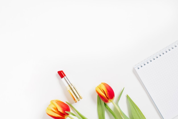 Flat lay with red tulip, notebook and lipstick