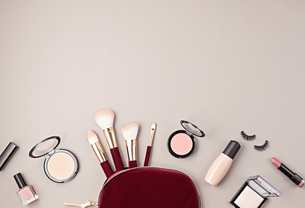 Flat lay with set of professional decorative cosmetics, makeup tools and woman accessories over gray wall with copy space. Beauty blog, fashion, party and shopping concept. Top view