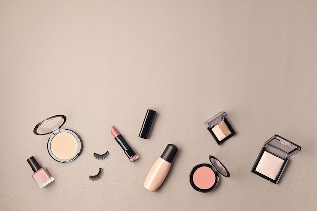 Flat lay with set of professional decorative cosmetics, makeup tools and woman accessories over gray wall with copy space. Beauty blog, fashion, party and shopping concept. Top view