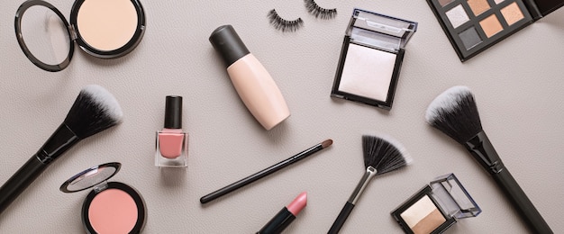 Flat lay with set of professional decorative cosmetics, makeup tools and woman accessories over gray wall with copy space. Beauty blog, fashion, party and shopping concept. Top view.