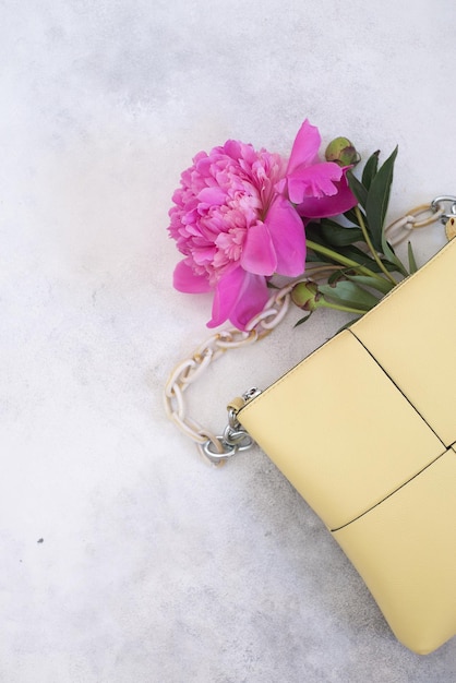 Flat lay of women handbag and pink peonies on a background Empty space for text Woman consept