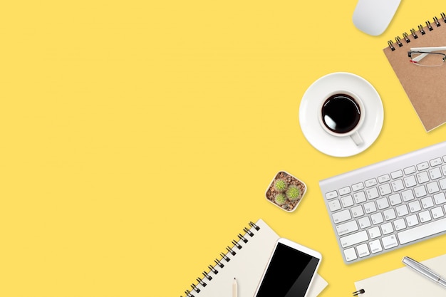 Flat lay workspace table with laptop computer, office supplies, coffee cup, tablet and cell phone on yellow pastel