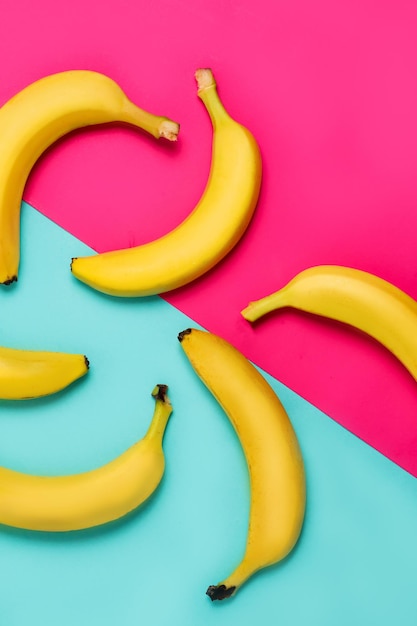 Flat lay of yellow bananas on blue and pink background