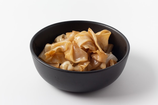 Flat noodles in bowl isolated on white background.