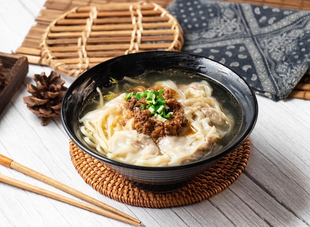 Flat noodles soup in a bowl isolated on wood table side view taiwan food