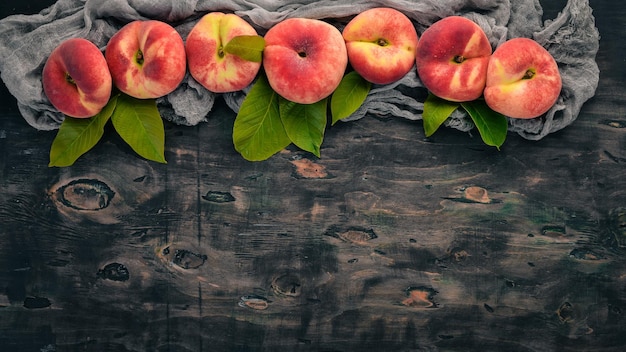 Flat peach with green leaves On a black wooden background Top view Free space for your text