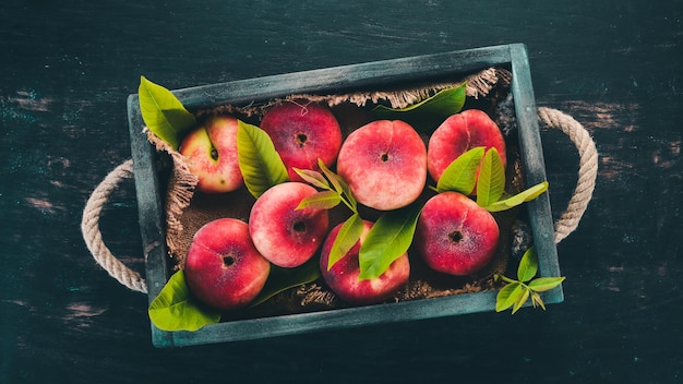 Flat peach in a wooden box On a black wooden background Top view Free space for your text