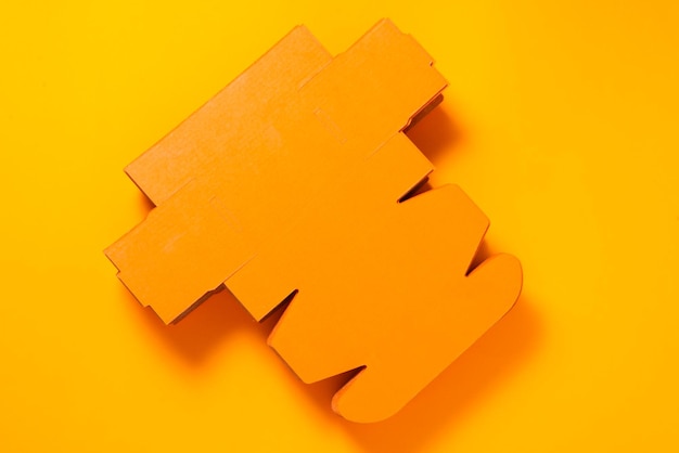 Flat unfolded cardboard box on orange background