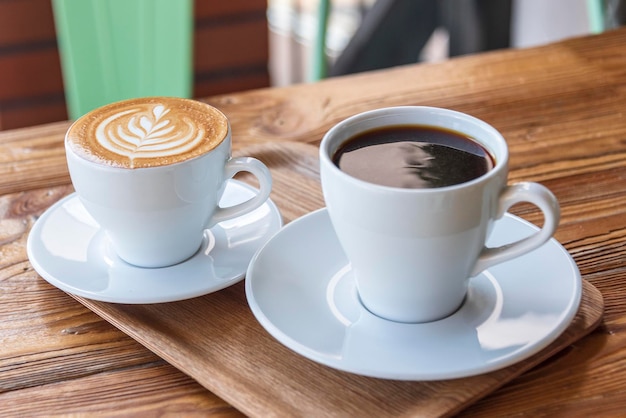 Flat white or cappuccino and filter coffee in white cups on wooden table Different coffee styles morning drink in cafe on small wooden tray