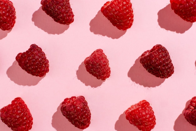 Flatlay of arranged raspberries on pink