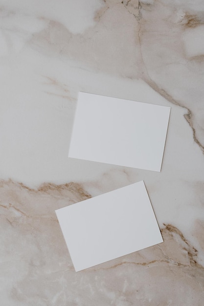 Flatlay of blank paper card on neutral beige marble background Business template Top view flat lay minimalist aesthetic luxury bohemian business branding concept