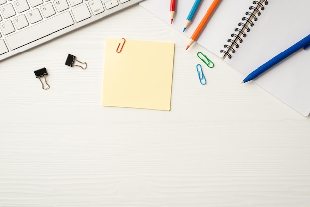 Flatlay above overhead close up frame border view photo of colorful pencils pen sheets of note paper open diary pc items isolated white wooden backdrop with blank empty space