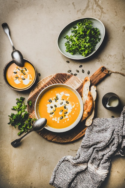 Flatlay of pumpkin cream soup with seeds parsley and cream