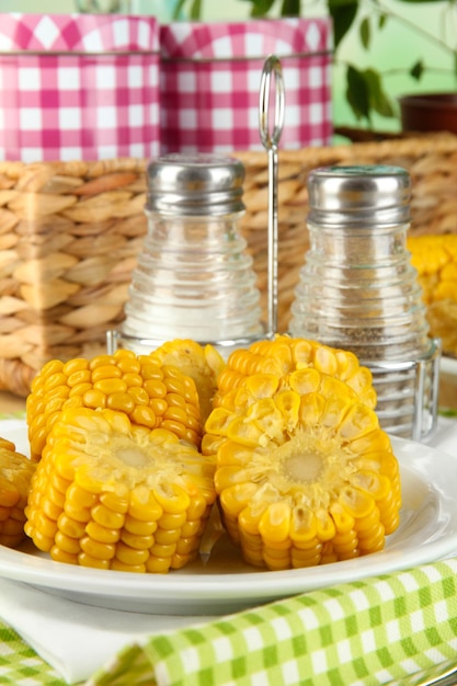 Flavored boiled corn on plate on wooden table on natural background