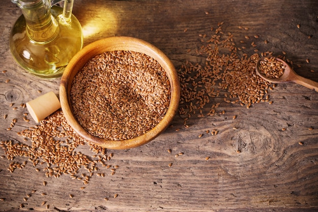 Flax seeds and linseed oil in a glass jug on a wooden table