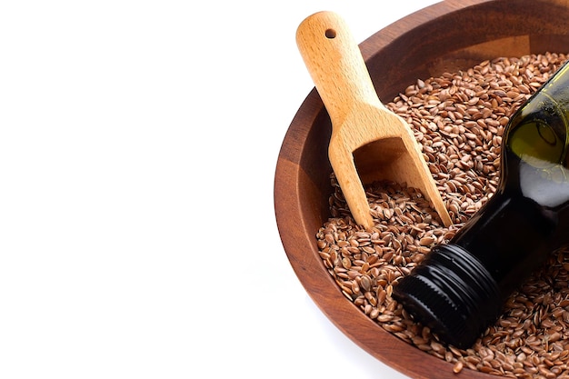 Flax seeds or linseeds in spoon and bowl with glass of linseed oil on wooden plate on white background Flaxseed or linseed concept Copy space