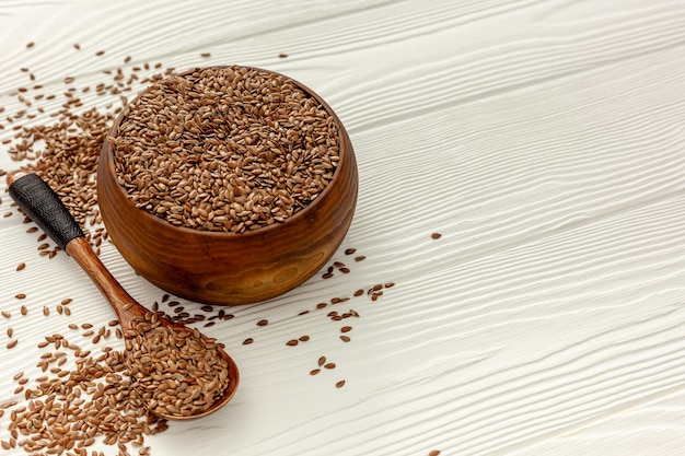 Flax seeds in a spoon and bowl with a bottle of flaxseed oil