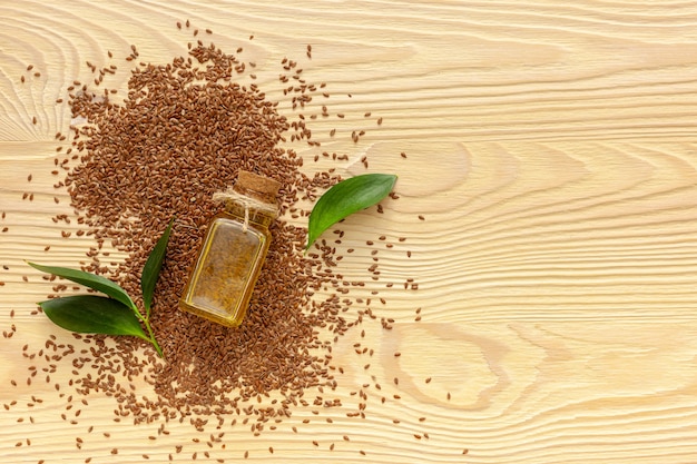 Flax seeds in a spoon and bowl with a bottle of flaxseed oil