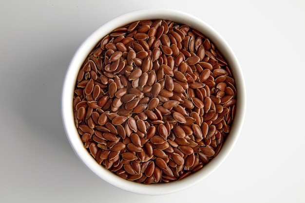 Flax seeds in a white ceramic bowl on a white background